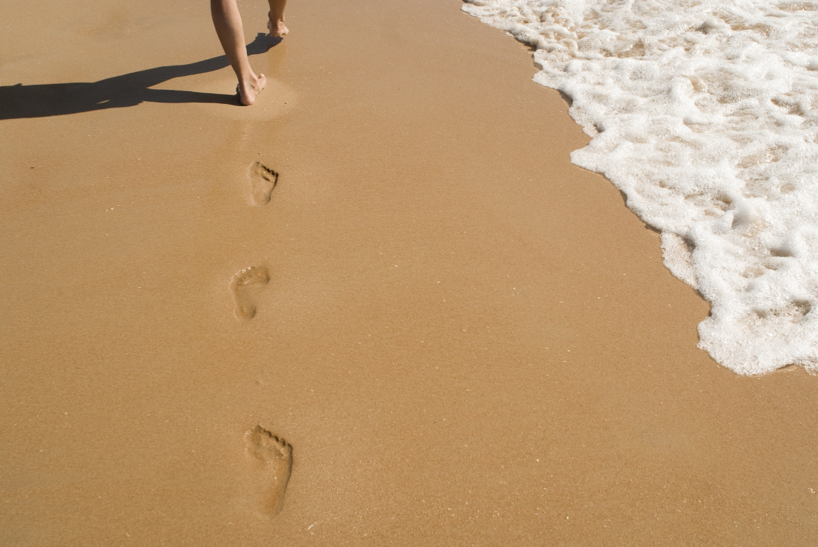 Empreintes de pas sur le sable représentant la trace durable laissée par une transformation ancrée dans le terrain.